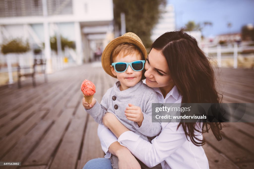 Young single mum hugging cute son who eats ice cream