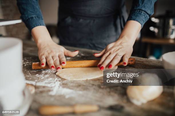 young woman kneading dough with rolling pin - rolling pin stock pictures, royalty-free photos & images