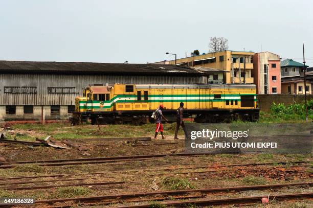 People pass an abandoned train at the Ebute-Metta headquarters of the Nigerian Railway Corporation in Lagos on March 7, 2017. Nigeria's acting...