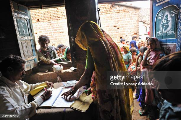 Indian men, women and children line up outside the Fair Price Shop with their ration cards to receive portions of wheat, sugar, kerosene and rice...