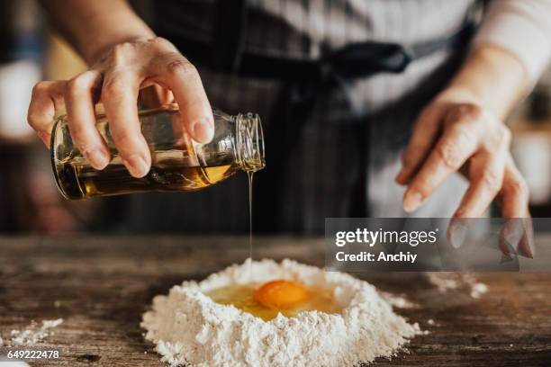 aggiunta di olio all'uovo e alla farina - tortellini foto e immagini stock