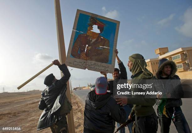 Opposition troops shoot at a portrait of Libyan leader Muammar al-Gaddafi as they celebrate after taking the city back from troops loyal to Gaddafi,...