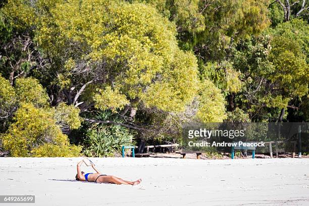 woman reading on whitehaven beach - whitehaven beach stockfoto's en -beelden