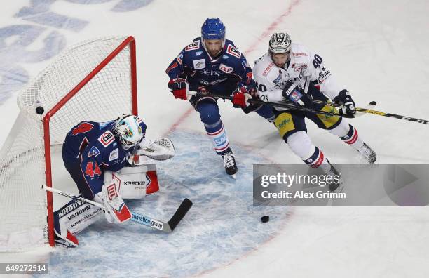 Darin Oliver of Berlin is challenged by Sinan Akdag and goalkeeper Dennis Endras of Mannheim during the DEL Playoffs quarter finals Game 1 between...