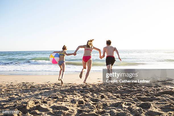 siblings running into the ocean - boy and girl running along beach holding hands stock-fotos und bilder