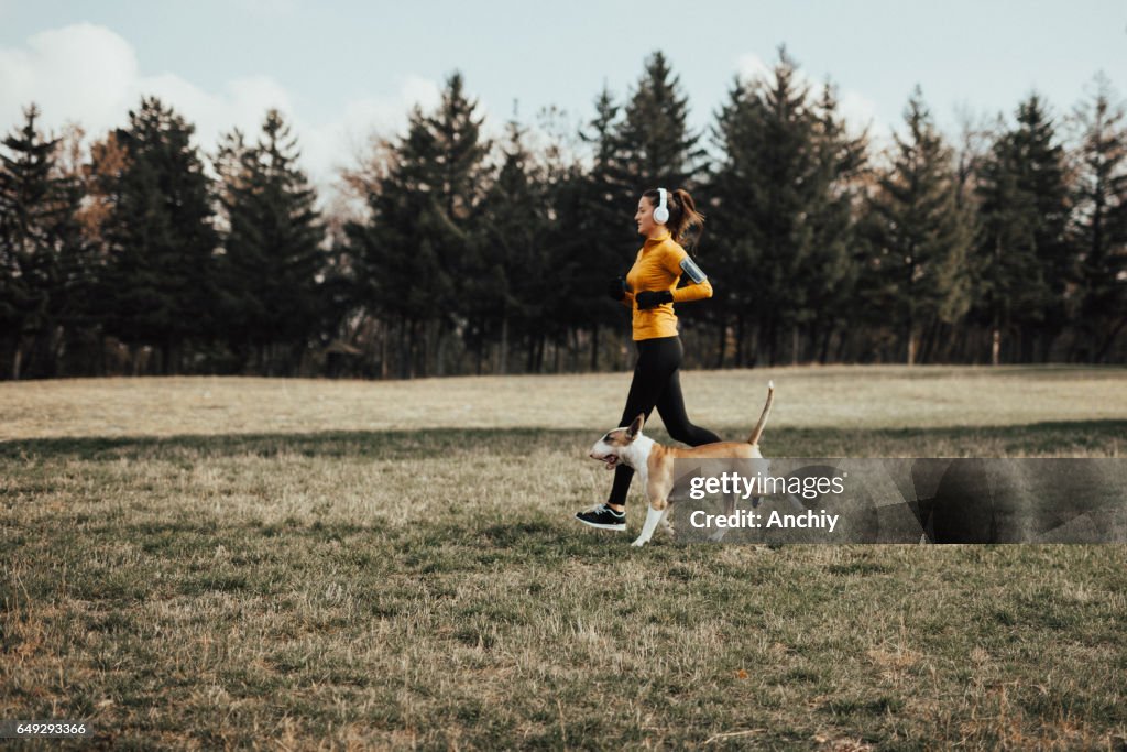 Young woman jogging in the park with her dog