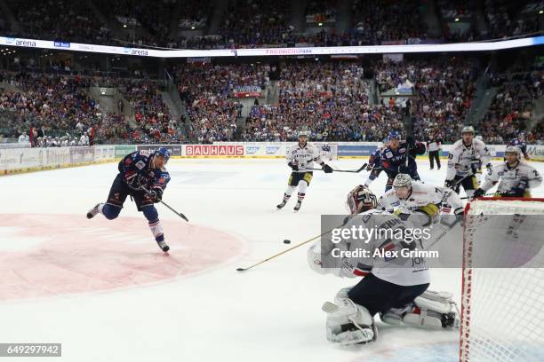 Aaron Johnson of Mannheim takes a shot at the goal against goalkeeper Petri Vehanen of Berlin during the DEL Playoffs quarter finals Game 1 between...