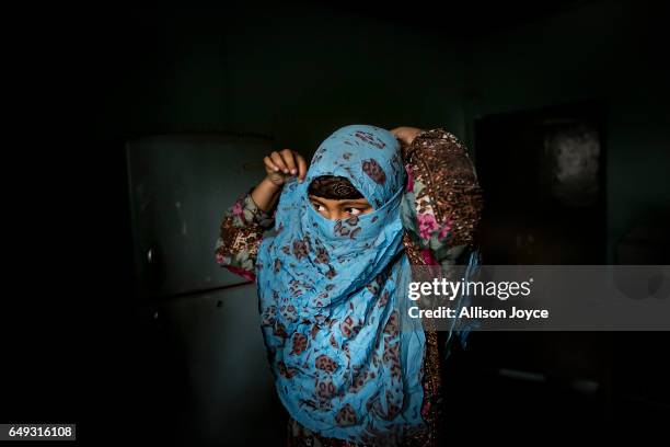 Rani ties her scarf around her face before leaving her home to take a school exam March 6, 2017 in Khulna division, Bangladesh. Rani, who is now 16,...