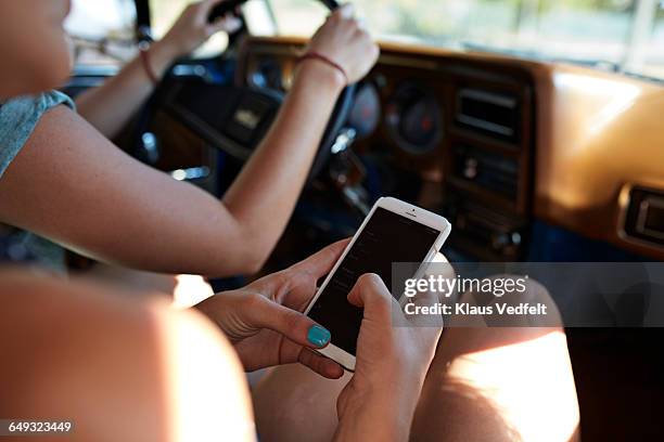 hands of passenger scrolling on phone inside car - car passenger stock pictures, royalty-free photos & images