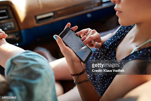 woman looking at map on phone, inside car - car exterior rear high angle stock-fotos und bilder