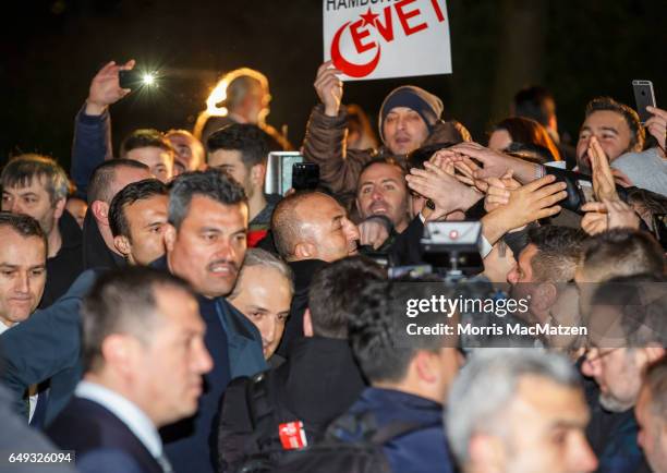 Turkish Foreign Minister Mevlut Cavusoglu emerges from the Turkish consulate after speaking to supporters of the upcoming referendum in Turkey on...