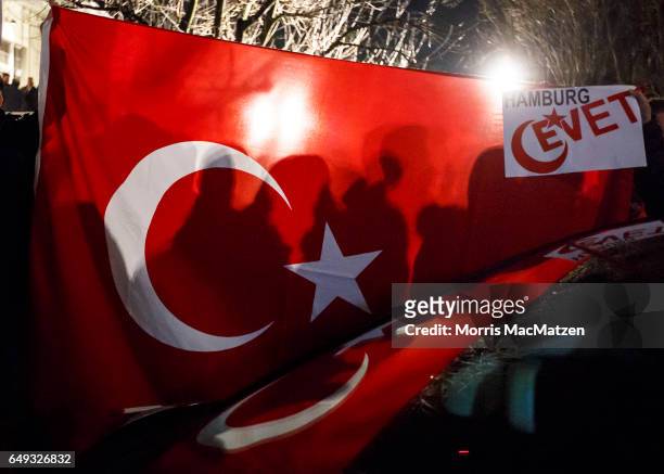 Supporters wave flags as Turkish Foreign Minister Mevlut Cavusoglu emerges from the Turkish consulate after speaking to supporters of the upcoming...
