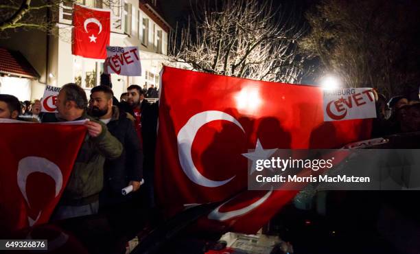 Supporters wave flags as Turkish Foreign Minister Mevlut Cavusoglu emerges from the Turkish consulate after speaking to supporters of the upcoming...