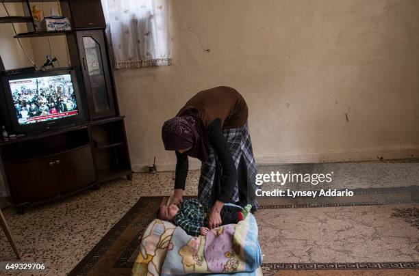 Emneh puts her youngest child to sleep in front of a television broadcasting anti-regime protests taking place across the border in Syria, in Tyre,...