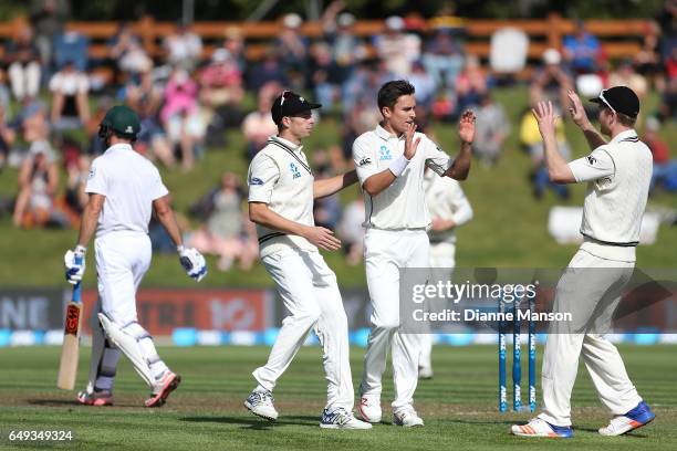 Mitchell Santner Trent Boult, and Jimmy Neesham of New Zealand celebrate the dismissal of Stephen Cook of South Africa during day one of the First...