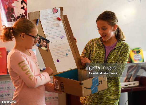 Brookelynn Johnson, left, helps Ashley Mackenzie with her I Am From poem project in their 6th grade Girls Athletic Leadership School 101 class March...