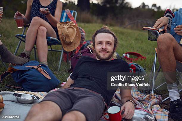 portrait of young man on camping trip - mann lässig gras sitzen stock-fotos und bilder