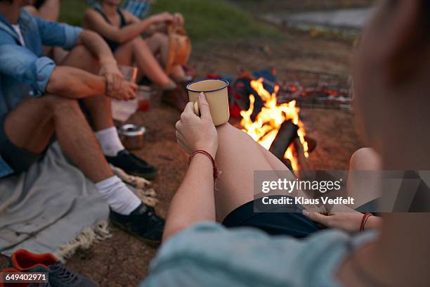 pov of female hands holding tincup, at campsite - men drinking around campfire stock pictures, royalty-free photos & images