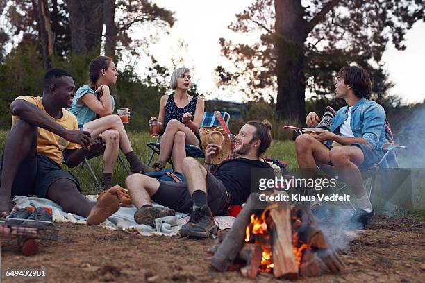 friends hanging out at campsite with bonfire - fuego al aire libre fotografías e imágenes de stock