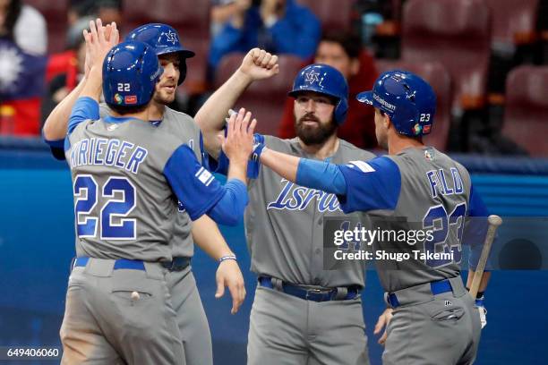 Tyler Krieger, Ryan Lavarnway and Cody Decker of Team Israel are greeted by teammate Sam Fuld after they all scored a run in the seventh inning...