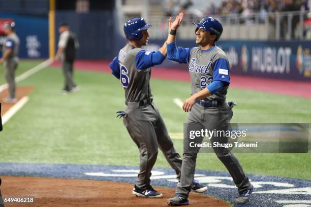 Sam Fuld of Team Israel greets teammate Ty Kelly at home plate after they both scored runs in the first inning during Game 2 of Pool A against Team...