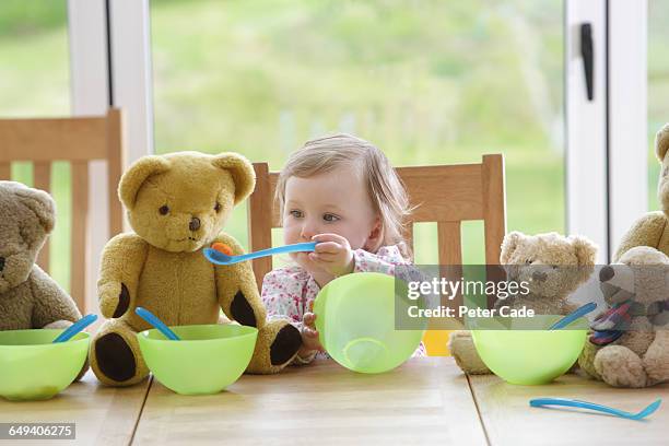 toddler feeding teddy bears at table - baby eating toy foto e immagini stock