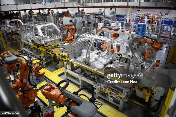 Robotic systems work on the chassis of a car during an automated stage of production at the Jaguar Land Rover factory on March 1, 2017 in Solihull,...