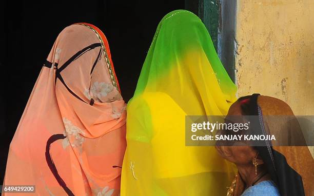 Indian voters queue as they await their turn to cast their votes at a polling station in Varanasi on March 8 during the last phase of state assembly...