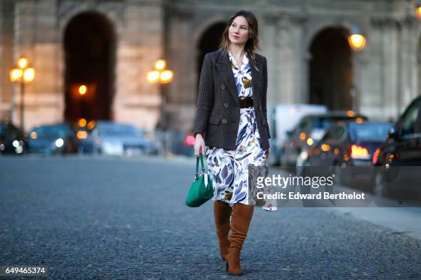Angelica Ardasheva wears a blazer jacket, a flower print dress, brown suede boots, and a green bag, outside the Louis Vuitton show, during Paris...