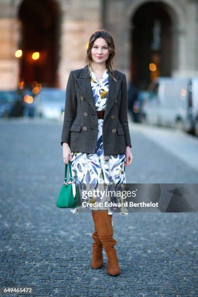 Angelica Ardasheva wears a blazer jacket, a flower print dress, brown suede boots, and a green bag, outside the Louis Vuitton show, during Paris...