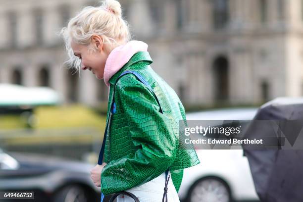 Olga Karput wears a pink hoodie sweater, a green jacket, jeans pants, a black bag, and black boots, outside the Louis Vuitton show, during Paris...