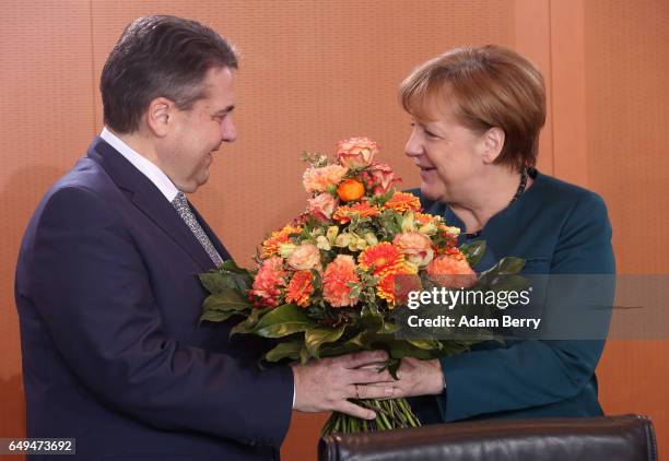 German Chancellor Angela Merkel gives flowers to Vice Chancellor and Foreign Minister Sigmar Gabriel in celebration of the birth of his baby daughter...