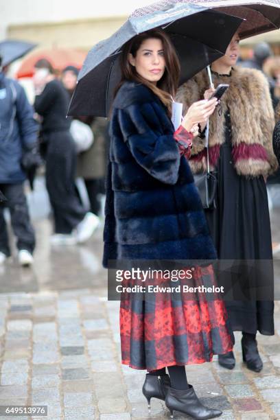 Guest wears a fluffy coat, and red skirt,, and an umbrella, outside the Celine show, during Paris Fashion Week Womenswear Fall/Winter 2017/2018, on...