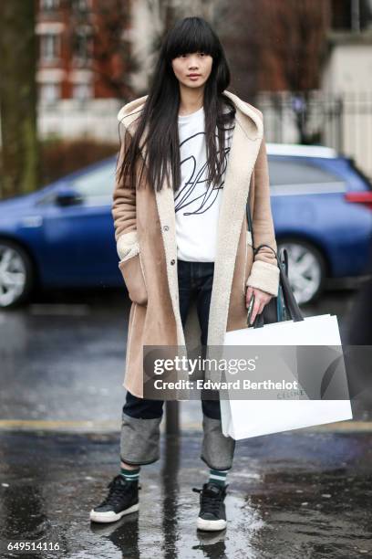 Guest wears a beige coat, with fluffy inner lining, outside the Celine show, during Paris Fashion Week Womenswear Fall/Winter 2017/2018, on March 5,...