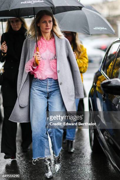 Guest wears a pink top, a gray coat, and blue jeans, outside the Celine show, during Paris Fashion Week Womenswear Fall/Winter 2017/2018, on March 5,...