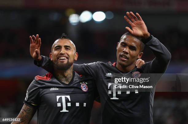 Arturo Vidal of Bayern Muenchen celebrates with Douglas Costa as he scores their fifth goal during the UEFA Champions League Round of 16 second leg...