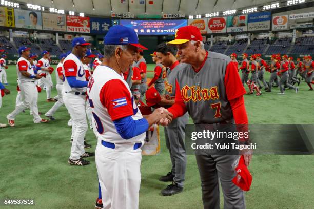 Managers John McLaren of Team China and manager Carlos Marti of Team Cuba exchange hats prior to Game 2 of Pool B at the Tokyo Dome on Wednesday,...