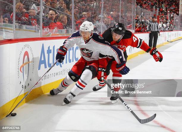 Lauri Korpikoski of the Columbus Blue Jackets skates around Karl Stollery of the New Jersey Devils at the Prudential Center on March 5, 2017 in...