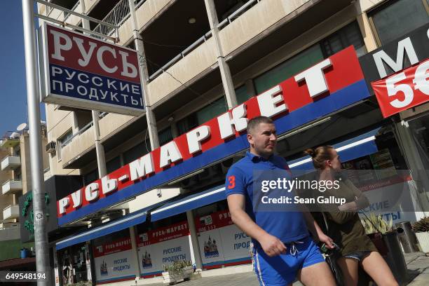 Couple walk past a Russian supermarket on March 8, 2017 in Limassol, Cyprus. Cyprus has largely recovered from its 2012-2013 economic crisis. The...