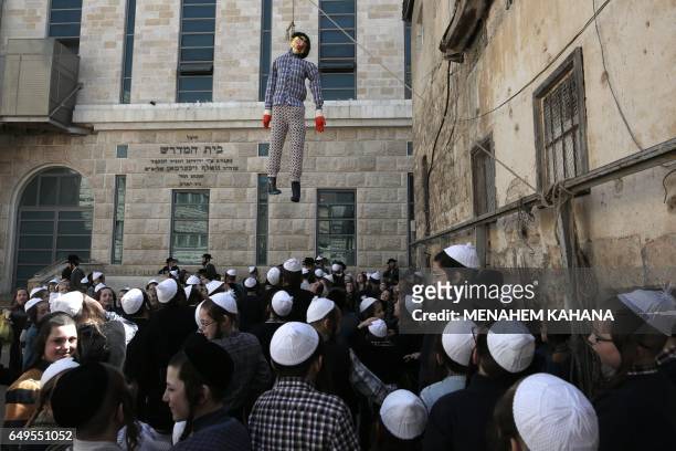 Ultra-Orthodox Jewish children look at a hanged figure doll symbolising the Evil Haman from the ancient Book of Ester, during their school Purim...
