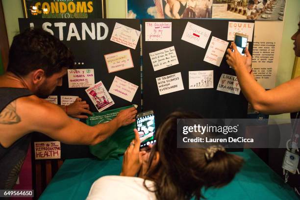 Participants in the Women's Strike in Bangkok take photos of the "I stand for" board posted at the event on March 8, 2017 in Bangkok, Thailand....