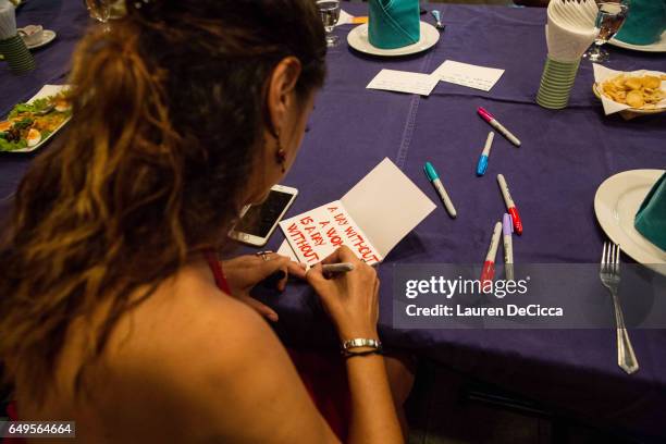 Women write their personal messages on index cards to be posted on the "I stand for" message board where women share why they strike on March 8, 2017...