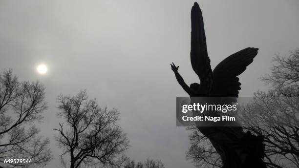 silhouette of a gravestone with the sun in clouds. - 埋葬地 ストックフォトと画像