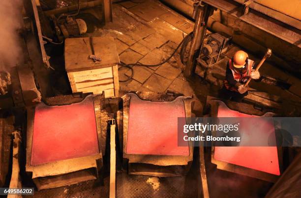 Worker hammers a copper cathode sheet as it cools in its mold in the copper smelting shop at the Uralelectromed OJSC Copper Refinery, operated by...