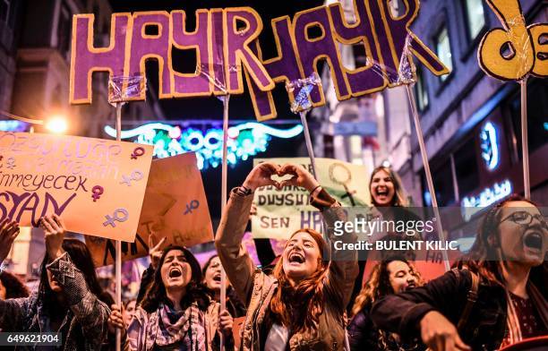 Woman makes a heart sign with her hands as people hold signs reading "no" as they march down Istiklal Avenue during a feminist night march to mark...
