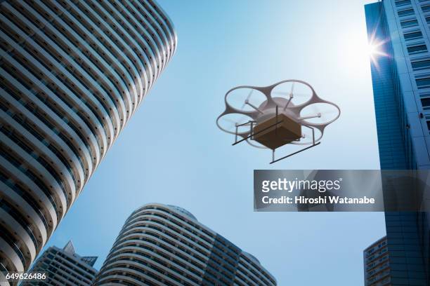 delivery drone flying above high rise apartments - drone foto e immagini stock