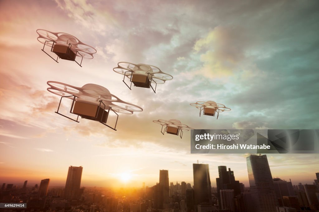 Five delivery drones flying above the city at sunset