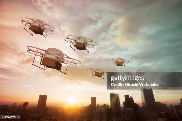 five delivery drones flying above the city at sunset - drones stock pictures, royalty-free photos & images
