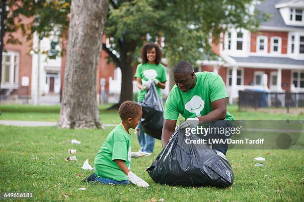 family picking up garbage in park - kids with cleaning rubber gloves stock-fotos und bilder