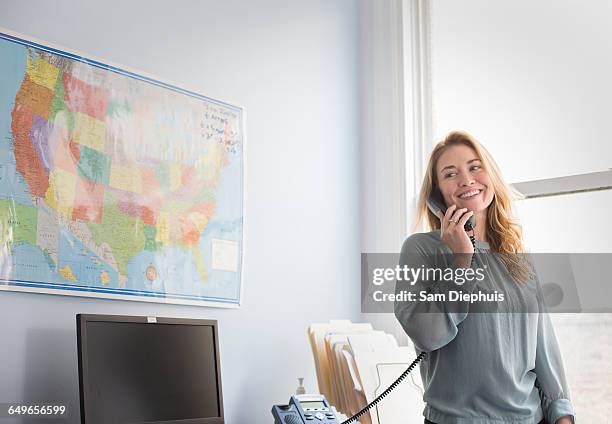 caucasian businesswoman talking on telephone in office - teléfono con cable fotografías e imágenes de stock